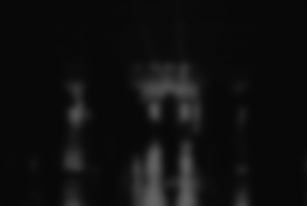 Blurry black and white image of figures in a dark setting.